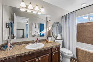 Bathroom featuring vanity, shower / bath combo, and a ceiling fan