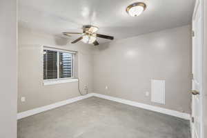 Spare room with a textured ceiling, concrete flooring, and a ceiling fan