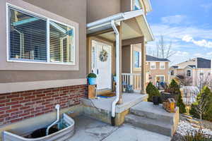 View of exterior entry featuring covered porch and stucco siding
