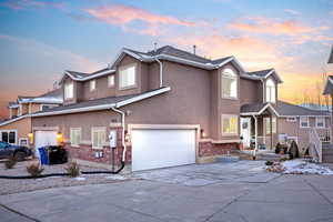 Traditional-style home with brick siding, stucco siding, concrete driveway, and a garage