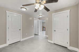 Unfurnished bedroom with finished concrete flooring and a ceiling fan