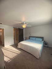 Carpeted bedroom with a barn door, ceiling fan, and a textured ceiling