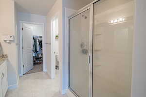 Full bathroom featuring vanity, a spacious closet, a stall shower, and light tile patterned floors