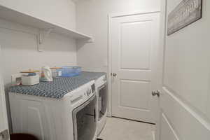 Laundry room with light tile patterned floors and washing machine and clothes dryer