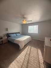 Carpeted bedroom with a ceiling fan and a textured ceiling