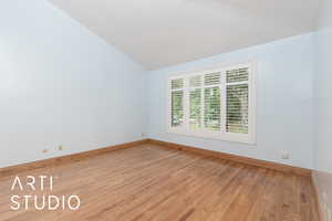 Spare room featuring lofted ceiling and light wood-style flooring
