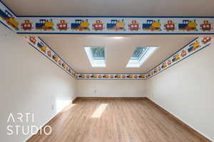 Unfurnished room featuring light wood finished floors and a skylight