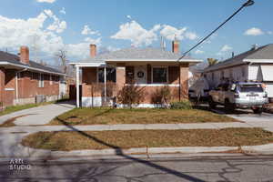 Bungalow-style house with brick siding, a chimney, and a front lawn