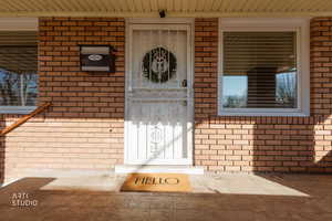 Doorway to property featuring brick siding and covered porch