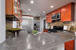 Kitchen featuring tasteful backsplash, stainless steel appliances, brown cabinets, and recessed lighting