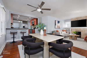 Dining room with dark wood-style flooring, a tile fireplace, a ceiling fan, and recessed lighting