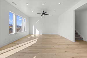 Unfurnished living room featuring recessed lighting, light wood-style floors, stairs, and a ceiling fan