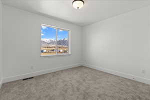 Empty room with a mountain view and light colored carpet