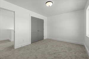 Unfurnished bedroom featuring light carpet and a closet