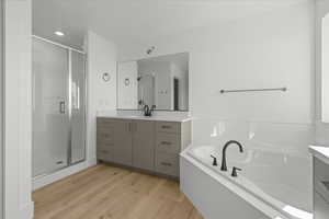 Full bath with vanity, a bath, a shower stall, and light wood-style floors
