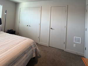 Carpeted bedroom featuring a textured ceiling and multiple closets