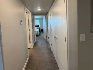 Hallway featuring a textured ceiling and dark colored carpet