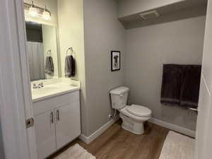 Full bath featuring a textured ceiling, vanity, dark wood-style flooring, and a shower with shower curtain