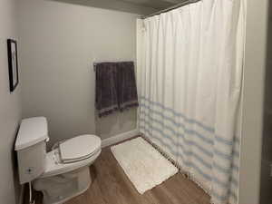 Full bathroom featuring curtained shower, dark wood-style floors, and a textured ceiling