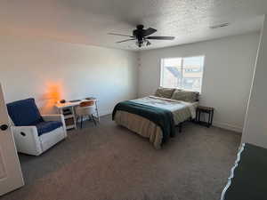 Carpeted bedroom featuring ceiling fan and a textured ceiling