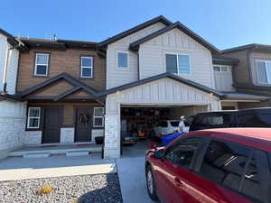 View of front of property featuring board and batten siding, a garage, stone siding, driveway, and covered porch