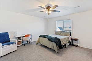 Bedroom featuring a ceiling fan, light colored carpet, and a textured ceiling
