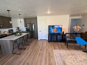 Kitchen featuring a breakfast bar, modern cabinets, a textured ceiling, appliances with stainless steel finishes, and a kitchen island