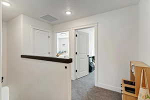 Hall featuring carpet and a textured ceiling
