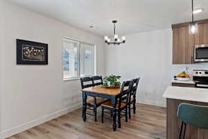 Dining area featuring light wood-style flooring, a textured ceiling, and a chandelier