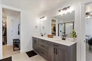 Bathroom featuring a walk in closet, a stall shower, double vanity, light colored carpet, and a textured ceiling