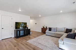Living area with light wood finished floors, a textured ceiling, and recessed lighting