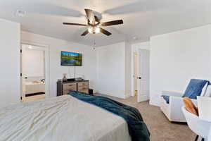 Bedroom with light carpet, a textured ceiling, a ceiling fan, and ensuite bath
