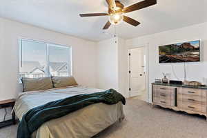 Bedroom with light carpet, a textured ceiling, and ceiling fan