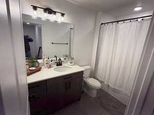 Bathroom with vanity, dark tile patterned floors, shower / tub combo with curtain, and a textured ceiling