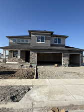Prairie-style house featuring stone siding, covered porch, and a garage