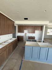 Kitchen with a textured ceiling and brown cabinets