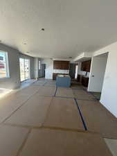 Unfurnished living room featuring baseboards and a textured ceiling