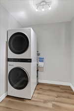 Washroom featuring stacked washer / dryer and light wood-style floors