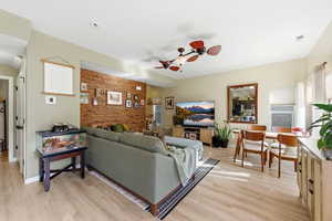 Living room with ceiling fan, light wood-type flooring, and an accent wall