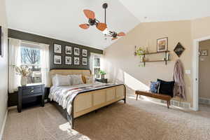 Bedroom with light colored carpet, vaulted ceiling, and a ceiling fan