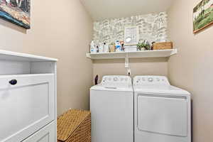 Washroom with washing machine and clothes dryer and wallpapered walls