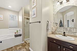 Full bathroom with vanity, a bath, and a stall shower