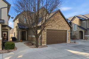 View of front of property with driveway, stone siding, stucco siding, and an attached garage