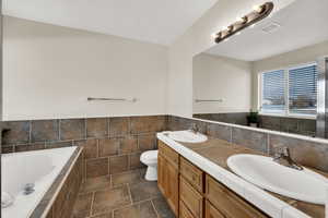 Bathroom featuring double vanity, a garden tub, tile walls, and wainscoting