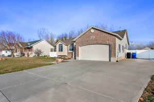 Ranch-style house with concrete driveway, brick siding, and a garage