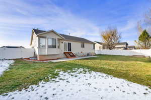 Snow covered rear of property featuring entry steps, a gate, a fenced backyard, and a patio area