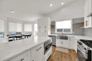 Kitchen with open shelves, light stone countertops, backsplash, and lofted ceiling