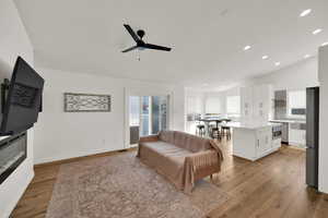 Living area featuring light wood-type flooring, recessed lighting, vaulted ceiling, and ceiling fan