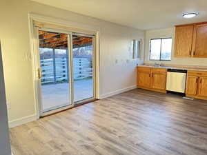 Kitchen featuring light countertops, stainless steel dishwasher, light wood finished floors, and brown cabinetry