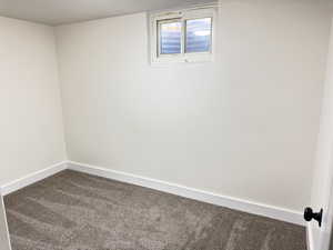 Carpeted spare room featuring baseboards